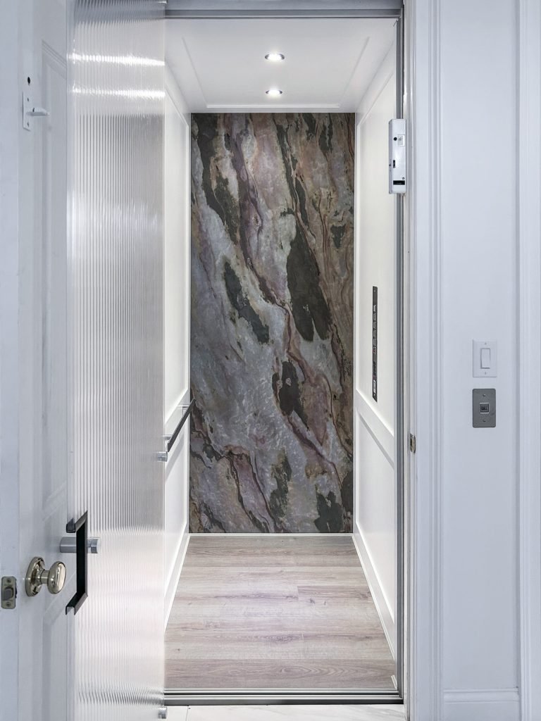 Natural stone back wall on a Shaker design home elevator cab.